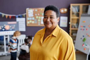 school counselor standing in a classroom with little children behind her